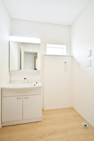 伊奈町本町第3　全2棟　1号棟の独立洗面台|収納力に優れた三面鏡付のシャワー付き洗面台を採用。鏡裏に小物を整理でき、洗面周りを常に清潔に保てます。洗濯機置場の上部には小窓があり、湿気がこもりがちなサニタリー空間に爽やかな風と光を届けます。