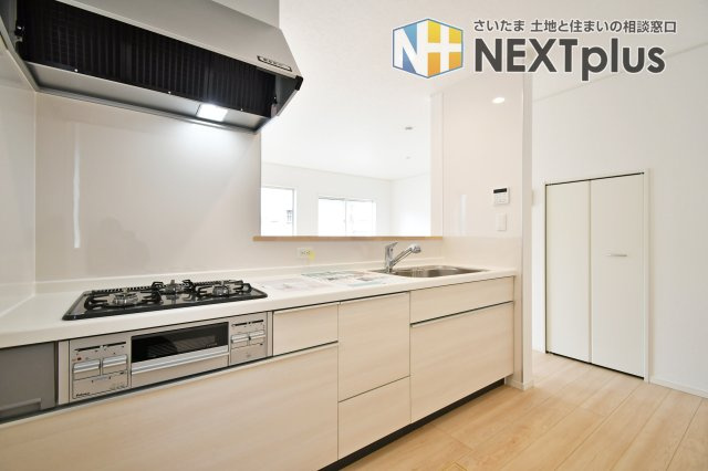 伊奈町本町第3　全2棟　1号棟のキッチン|お手入れしやすいガラストップコンロや浄水器内蔵シャワー水栓を搭載 。背後には冷蔵庫やカップボードを置くゆとりがあり、スムーズな家事動線を実現します。白を基調とした清潔感あるデザインも魅力です。