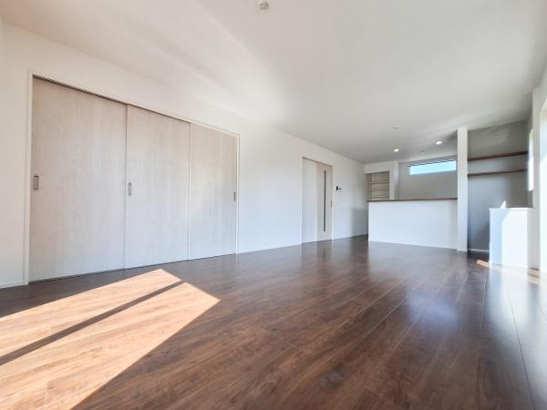 花高松2丁目1期1号棟の居間・リビング|大きな窓から自然光がたっぷりと入るリビングです。床の色が落ち着いた雰囲気を演出しています。収納スペースも充実しておりすっきりとした空間です。キッチンカウンターも設置されていて便利です。