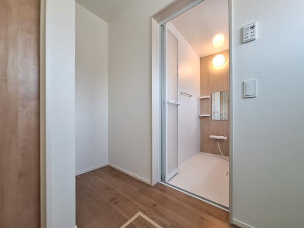 大字佐野1期3号棟の独立洗面台|ナチュラルな雰囲気の床材が印象的です。洗面所と洗面台がすっきりとしたデザインでまとまっています。明るい照明が設置されており空間全体がやわらかい印象となっています。