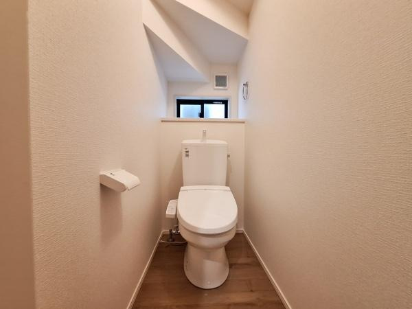 大字佐野1期3号棟のトイレ|清潔感のあるシンプルなトイレ空間です。窓があり自然光を取り入れることができます。壁や床材も明るめの色合いで開放的な印象です。天井の形状も特徴的なデザインです。