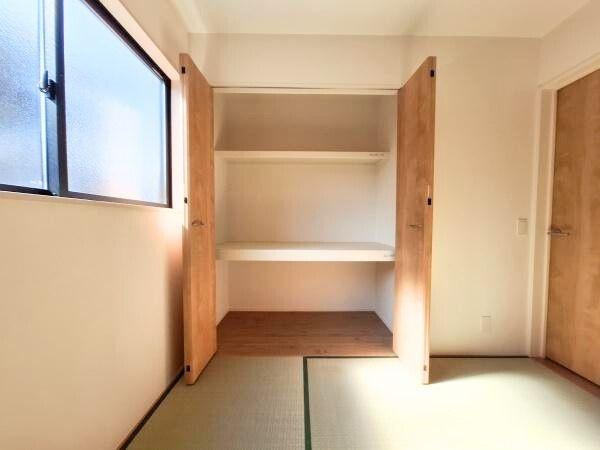 大字佐野1期3号棟の収納|収納スペースは観音開きの扉付きで使い勝手の良い棚が設けられています。収納内部は広々としておりさまざまなアイテムを整理できます。室内は明るく清潔感があり収納扉の木目調がインテリアに調和しています。