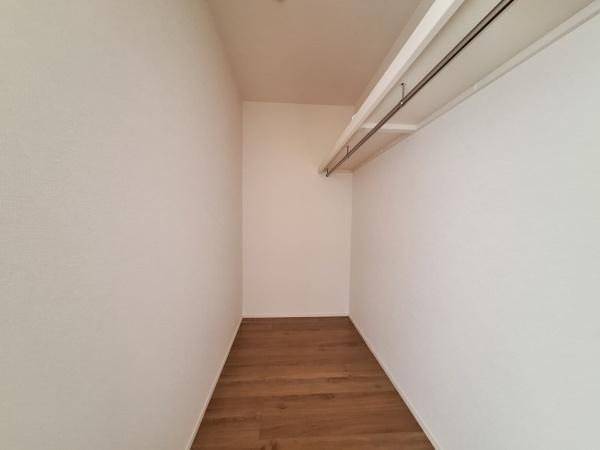 大字佐野1期3号棟の収納|広々とした収納スペースが用意されています。シンプルな内装で使いやすいデザインです。ハンガーパイプ付きで衣類の整理もしやすく壁面は清潔感があります。床は木目調で空間をすっきり見せます。