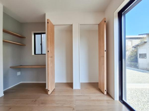 大字佐野1期3号棟の居間・リビング|リビングには大きな窓から自然光がたっぷり入り明るい空間が広がります。収納スペースも備えられており整理整頓がしやすい設計です。作業に便利なカウンターと棚も設置されているためさまざまな用途に対応できます。