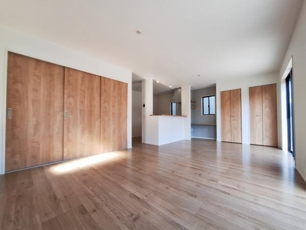 大字佐野1期3号棟の居間・リビング|ゆったりとしたリビングはナチュラルな木目調の床と扉が調和しています。明るい光が差し込み開放感があります。収納スペースも充実しています。シンプルなデザインで様々なインテリアに合わせやすい空間です。