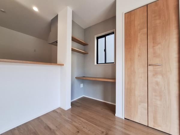 大字佐野1期3号棟の居間・リビング|リビングに設けられたカウンターが空間のアクセントになっています。ナチュラルな木目調の扉や棚が統一感を演出しています。窓からの自然光で明るい印象です。