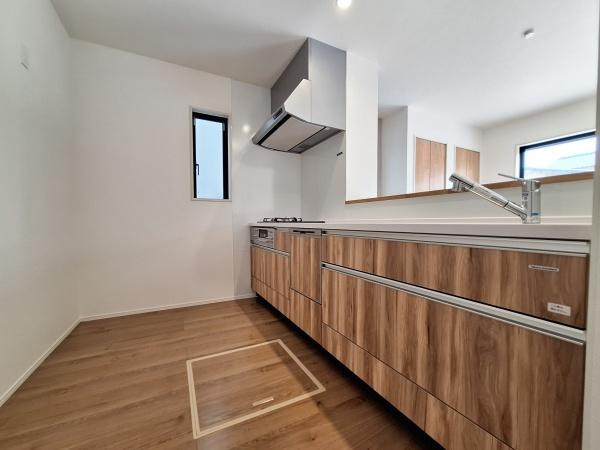 大字佐野1期3号棟のキッチン|木目調のデザインが特徴的なキッチンです。すっきりとしたレイアウトで収納スペースが多く確保されています。換気扇や窓も備わっており機能面にも配慮されています。