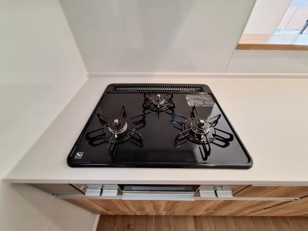 大字佐野1期3号棟のキッチン|キッチンのガスコンロは3口タイプで調理の効率が高まります。天板はフラットなのでお手入れも簡単です。カウンターのスペースも広く使いやすい印象です。