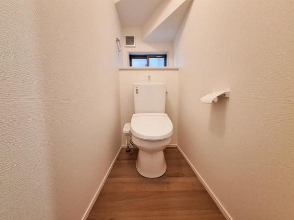 大字佐野1期2号棟のトイレ|清潔感のある内装が特徴のトイレです。木目調の床で落ち着いた雰囲気が広がります。窓があり換気や採光にも配慮されています。