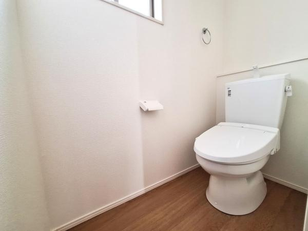 大字佐野1期1号棟のトイレ|清潔感のあるシンプルなデザインが特徴のトイレです。明るい色合いの壁と床が空間をより広く感じさせます。小窓が設けられており換気もしやすい仕様です。
