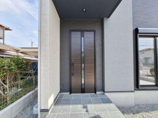 星和台2丁目1期1号棟の玄関|玄関はシンプルで洗練されたデザインが特徴です。落ち着いたカラーの玄関ドアが外観と調和しています。十分なスペースが確保されているアプローチ部分は屋根付きで、雨の日でも安心です。