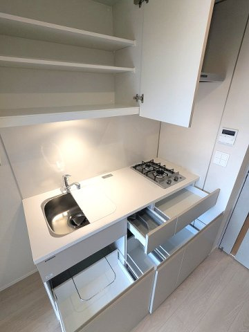 SEASON FLATS浅草六丁目のキッチン|ガス2口システムキッチン、料理やすい様にシンクカバー付、奥まで収納しやすいスライド式の収納