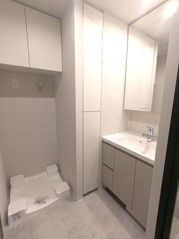 SEASON FLATS浅草六丁目の洗面所|トイレと独立した洗面脱衣室、2面鏡付ハンドシャワー付洗面台、洗面台下にはヘルスメーターストックあります、洗濯機置場は排水口のお手入れしやすい様に手前中央に配置し、足高の防水パンです