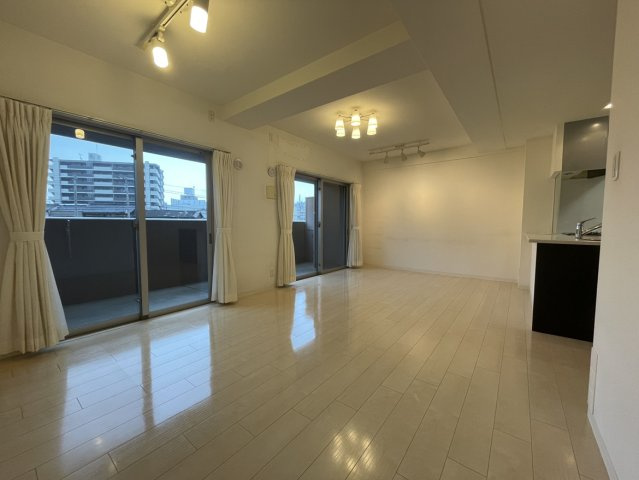 アルファステイツ市駅西の居間・リビング|15畳以上の広さを持つLDKは、南東向きの大きな窓から心地よい陽光が室内にたっぷりと差し込みます。白を基調とした明るい空間で、大きめのソファを置いてもゆとりがあり家族が集まる憩いの場になります。
