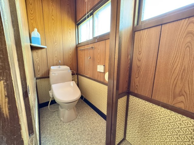 【角地の開放感】昭和エリアの利便性と、木の温もりあふれる室内が魅力の住まいのトイレ|温水洗浄便座付きのトイレ。壁紙の模様がレトロなアクセントに。