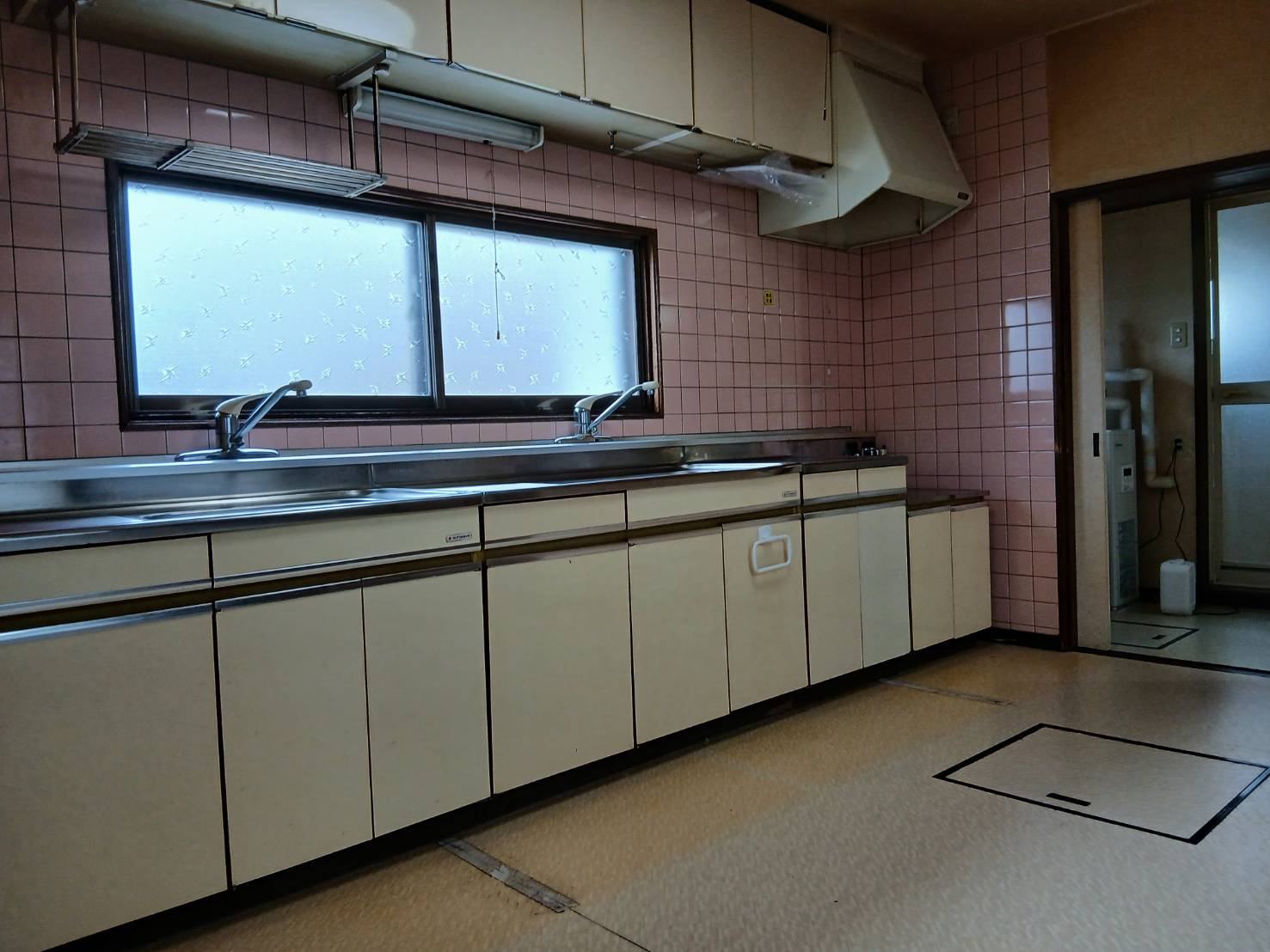 【角地の開放感】昭和エリアの利便性と、木の温もりあふれる室内が魅力の住まいのキッチン|調理動線の良い壁付けキッチン。窓からの光が手元を明るく彩る。