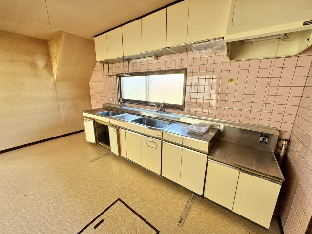 【角地の開放感】昭和エリアの利便性と、木の温もりあふれる室内が魅力の住まいのキッチン|調理動線の良い壁付けキッチン。窓からの光が手元を明るく彩る。