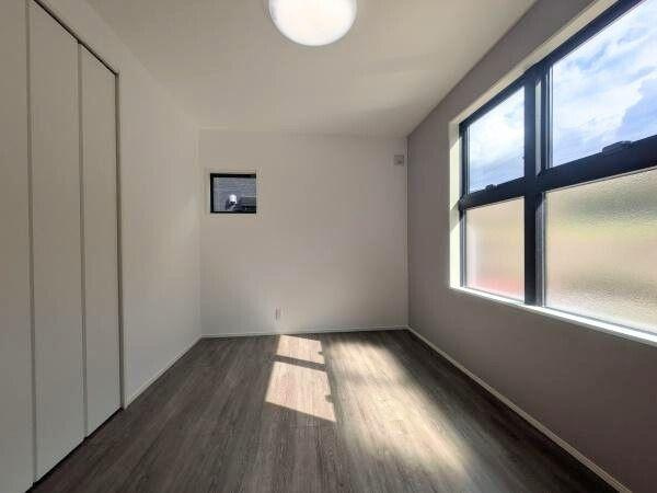 タマタウン横尾東町2　2号地の洋室|洋室には大きな窓から豊かな光が差し込み明るい空間が広がっています。落ち着いたフローリングが室内の印象を引き締めています。収納スペースも備わっており使い勝手の良い設計です。