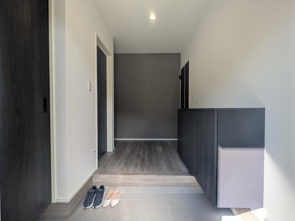 タマタウン横尾東町2　2号地の玄関|明るい光が差し込む玄関は清潔感のあるシンプルなデザインです。収納スペースも確保されており日々の出入りが快適に行えます。落ち着いた色使いが空間を引き締めています。壁や床の素材感がしっかりと感じられます。
