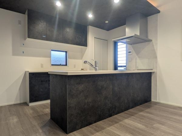 タマタウン横尾東町2　2号地のキッチン|ダークカラーを基調としたキッチンはモダンな雰囲気を演出しています。カウンターが広く使い勝手に配慮されたレイアウトです。天井まで続く収納スペースも備えられており空間の統一感が魅力です。