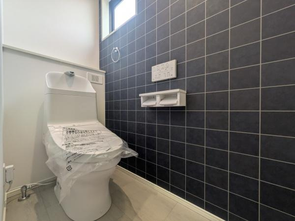 タマタウン横尾東町2　2号地のトイレ|黒のタイル調の壁が空間にメリハリを与えています。小窓が採光を確保し明るい印象をプラスします。