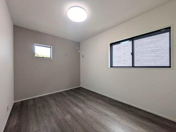 タマタウン横尾東町2　2号地の洋室|シンプルな内装で落ち着いた色合いの洋室です。大きな窓があり明るさをしっかり確保できます。床材の質感が空間を引き締めています。壁面もすっきりとした印象です。