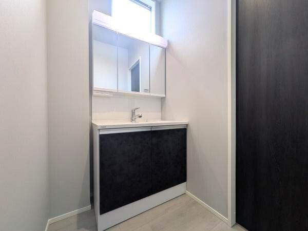 タマタウン横尾東町2　2号地の独立洗面台|洗面台・洗面所の写真です。明るい光が差し込む窓付きで清潔感のある白と黒のコントラストがポイントです。広々としたミラーと充分な収納スペースが備わっています。シンプルなデザインが空間を引き立てます。