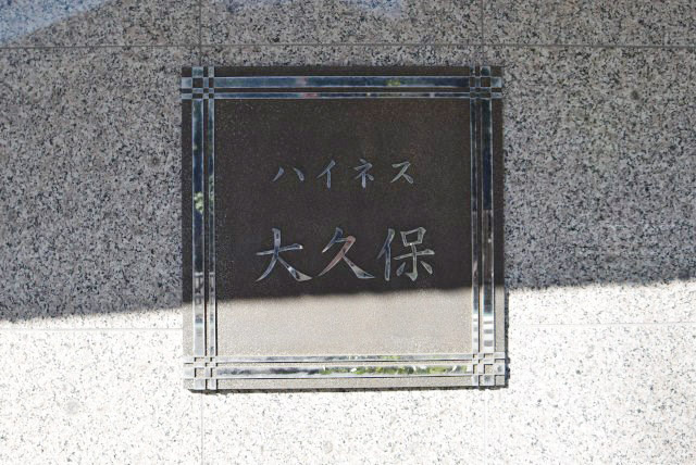 【現況写真】 | ハイネス大久保 | エントランスに掲げられた、マンション名を示す館銘板。さほど激しく主張はしませんが、しっかりと掲示されています。～即日のご見学可能～　お問合せはお気軽にどうぞ。