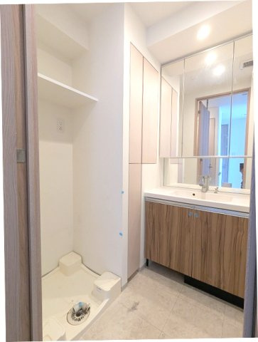 ORSUS(オルサス)三ノ輪の洗面所|トイレと独立した洗面脱衣室、三面鏡付ハンドシャワー付洗面台、洗面台の下にヘルスメーターストックあります、洗濯機置場は排水口のお手入れしやすい様に手前中央に配置し、足高の防水パンです