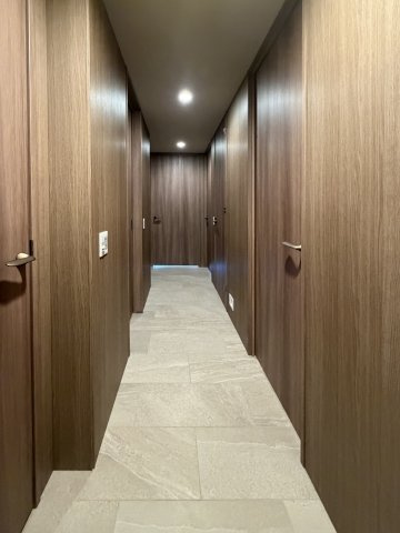 【専有部の廊下】壁はクロスではなく木板を使用。建具も壁も深みのあるブラウンで統一されておりホテルライクな落ち着きのある雰囲気を感じさせます。