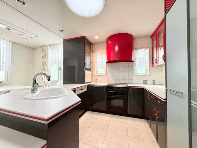 旭ヶ丘３丁目　戸建のキッチン|赤と黒で統一された印象的なデザインキッチン。海外邸宅のような雰囲気を感じさせる空間