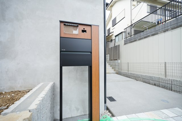 【吹抜けリビング×全室南西向きの明るい家】光と開放感に包まれる暮らし｜仲介手数料無料の設備|木目とブラックのコントラストが印象的なポスト。スタイリッシュなデザインが住まいの外観に調和し、すっきりとした印象を演出します。毎日の郵便物の受け取りもスマートに行える、機能性とデザイン性を兼ね備えた設