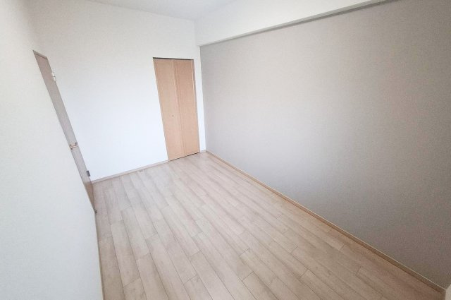 エスリード堺三国ヶ丘の洋室|洋室：リフォーム済みのナチュラルな床とグレーのアクセントクロスが調和するシンプルでやさしい空間。