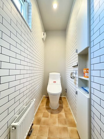 月寒東4条18丁目　一戸建てのトイレ|白基調のレンガ風壁紙が清潔感を演出するタンク一体型トイレスペース。収納力も◎