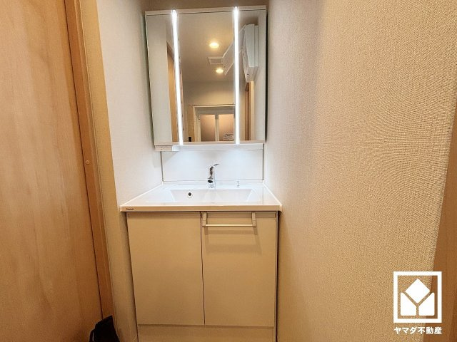 武庫川あおぞらのまち25号棟の独立洗面台|収納付きでスッキリお使い頂ける3面鏡の洗面台です。縦に2本配置されたLED照明が顔全体を明るく均等に照らしてくれるので、スキンケアやメイクがしやすくなります。