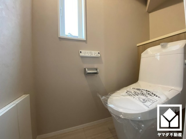 尼崎市金楽寺　1号地のトイレ|明るく清潔感溢れるトイレです。トイレットペーパーのストックや消耗品置き場、小物置きなどとしてもお使いいただける棚がございます。