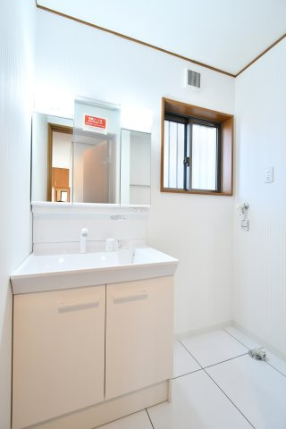 さいたま市見沼区深作2丁目の独立洗面台|新規交換された三面鏡付き洗面化粧台は、収納力も高く朝の準備もスムーズに。白を基調とした洗面室は、床フロアタイルも上貼り済みで毎日のお手入れが簡単です。窓付きで湿気対策のできる快適空間。