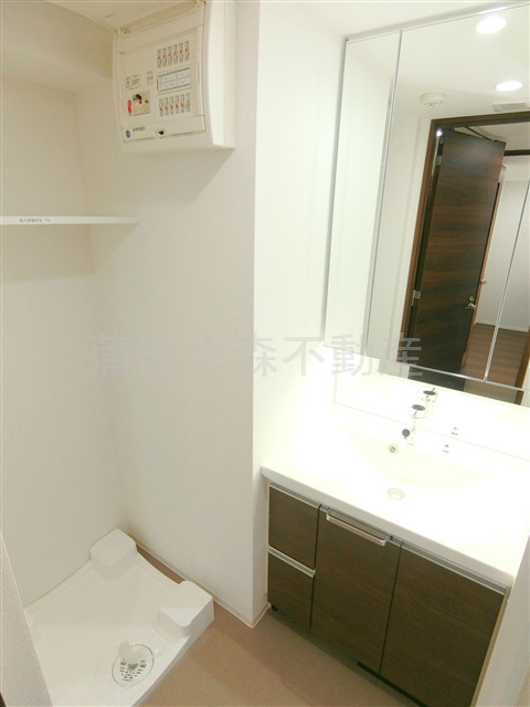 ブライズ蒲田EASTの洗面所|洗面脱衣所　3面鏡の独立洗面台　棚付きの洗濯機置き場