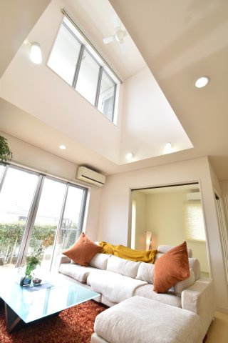 南ひな壇に建つ収納充実のモダン住宅の居間・リビング|リビング上部には吹き抜けがあり優しい光が降り注ぎます！電動カーテン付き。２階からもリビングが見渡せます！シーリングファンも付いています。
