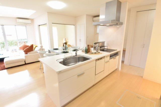 南ひな壇に建つ収納充実のモダン住宅のキッチン|アイランドキッチンは間取りの中心で、ダイニング・リビング、和室が見渡せます。食器洗い乾燥機付き！キッチンカウンターは広く、人工大理石を使っています。IHヒーターで火を使わないので安全です。
