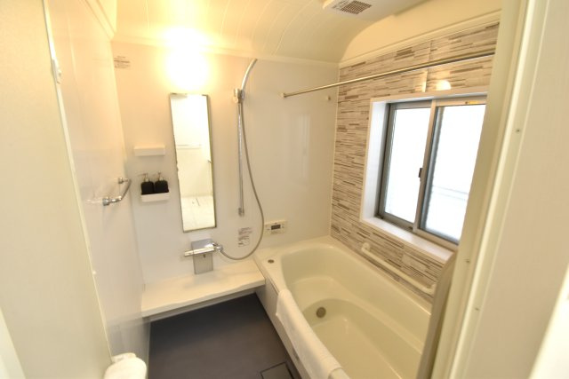 南ひな壇に建つ収納充実のモダン住宅の浴室|浴槽への出入りが安全な低床タイプのユニットバスです。洗い場は滑りにくい速乾床で断熱仕様ですので、ヒートショックの心配もありません。オール電化でエコキュート、浴室乾燥機付きのオートバスです。
