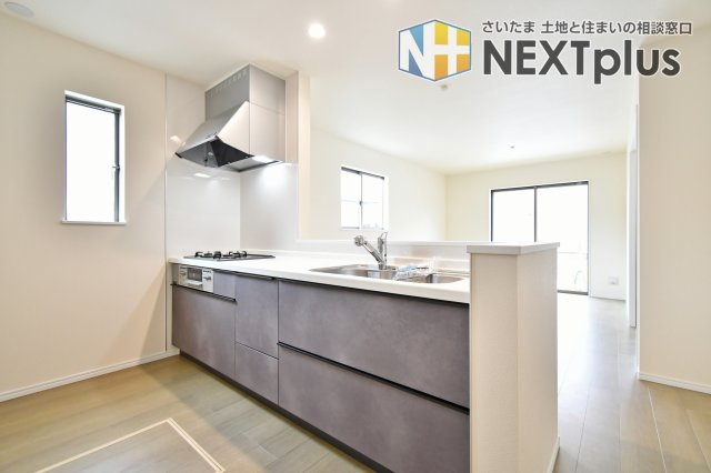 第17上尾上　全6棟　B号棟のキッチン|視界が開けたオープンキッチンからはリビングを一望でき、料理中も家族との会話が弾みます。グレーのシックなパネルが空間を引き締め、暮らしを彩る洗練されたインテリアのような美しさと機能性を両立しました。