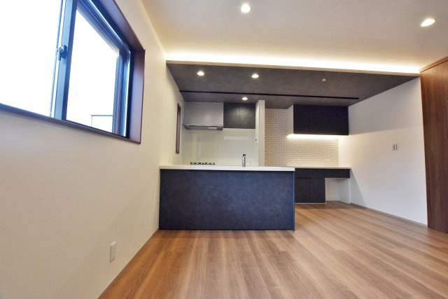 シャルムコート・ジョン上田中町｜3LDK＋駐車1台可の居間・リビング|リビング側からキッチンに向かって撮影した写真です。キッチン上部に折り下げ天井を配して空間に立体感が生まれます。ダウンライトも設置しているので機能性もアップしています。