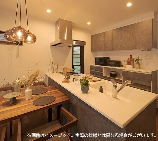 大在汐見　A棟のキッチン|落ち着いた色合いのキッチンが上品な印象です。カウンターが広く使いやすいレイアウトです。収納スペースも充実しています。