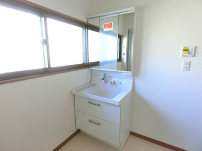 【独立洗面台】 | 【リフォーム住宅】中古一戸建　倉敷市中島　3LDK | シャワー付き三面鏡タイプの洗面化粧台へ交換。
鏡裏には小物をたっぷり収納でき、朝の身支度も効率的に。
シャワーヘッド付きで掃除もしやすい設計です。