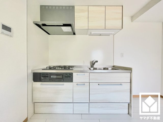 コボリマンション夙川老松台Ｄ棟のキッチン|使いやすさとデザイン性を両立。落ち着いた木目調のデザインが魅力のシステムキッチンです。壁付けタイプで空間を有効活用します。家族のごはん作りがもっとスムーズになる、便利な3口コンロ付き。