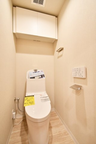 ソフィア上尾C棟のトイレ|清潔感あふれる温水洗浄便座に新規交換済み。上部には備品をスッキリ隠せる吊戸棚付きで、生活感を出しません。シンプルながらも機能的な空間は、リノベーション物件ならではの心地よさを提供します。