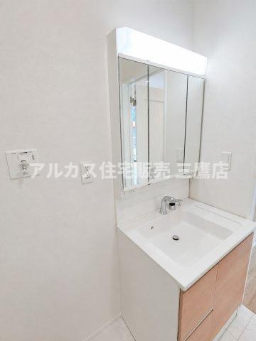 京王線 仙川駅 16分 新築戸建 三鷹市新川1丁目の独立洗面台|木目調のキャビネットと三面鏡裏収納を備えた、使い勝手の良い洗面化粧台。