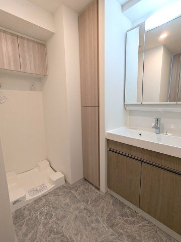 GRANSITE蔵前の洗面所|トイレと独立した洗面脱衣室、三面鏡付ハンドシャワー付洗面台、洗濯機置場は排水口のお手入れしやすい様に手前中央に配置し、足高の防水パンです