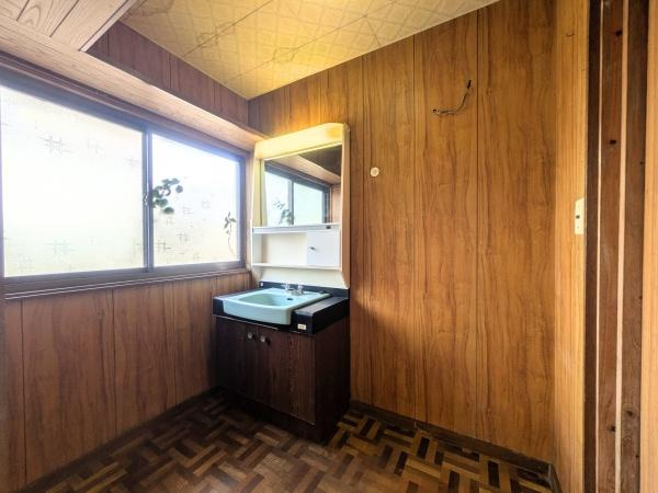 上田町3丁目　戸建ての独立洗面台|大きな窓から明るい光が入る洗面所です。木目調の壁と床が落ち着いた雰囲気を演出します。シンプルな洗面台は収納も備え付けられており使い勝手にも配慮されています。全体的にスペースが十分に確保されています。